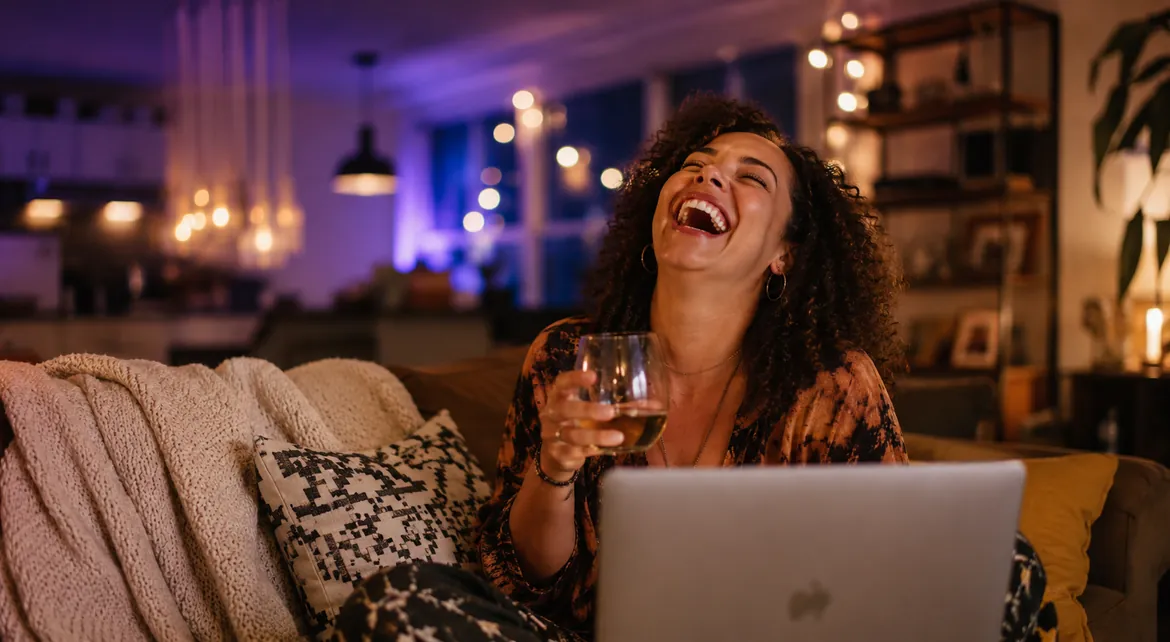A Couple member laughing with delight during a live online mixer at home